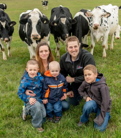 Farmer family posing in front of dairy cattle
