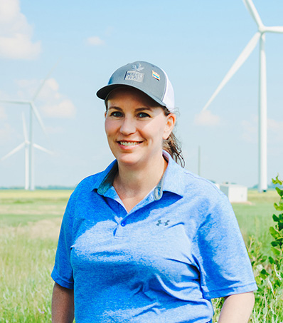 Woman in baseball cap standing in front of windmills