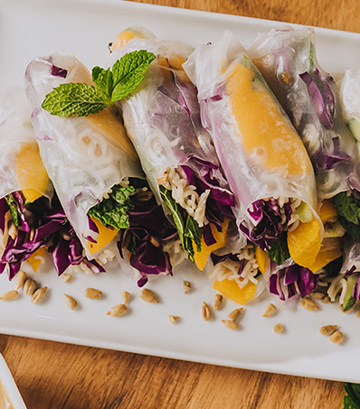 A plate of stacked Peach Sunflower Seed Salad Rolls garnished with a sprig of mint.